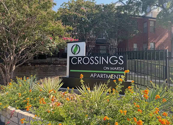 A sign for Crossings on Marsh apartments is surrounded by flowers.