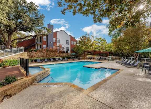 A swimming pool surrounded by trees and chairs.