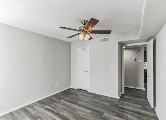 A room with a ceiling fan and a door.