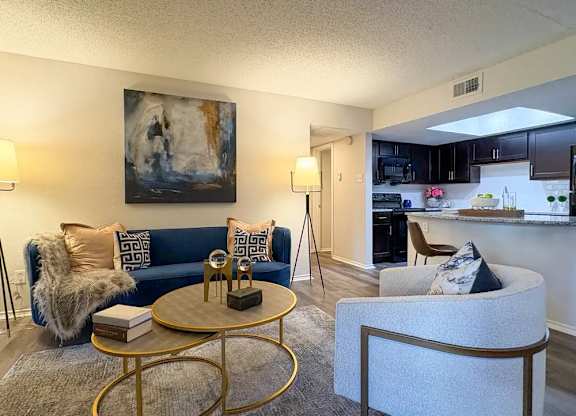 A living room with a blue couch and a painting on the wall.