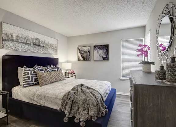 A bedroom with a bed, nightstand, and a mirror.