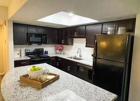 A kitchen with black cabinets and a granite countertop.