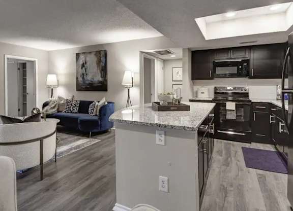 A modern kitchen with a black refrigerator and a dining table with chairs.