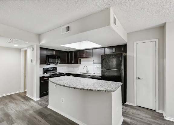 A kitchen with a black refrigerator and a white island.