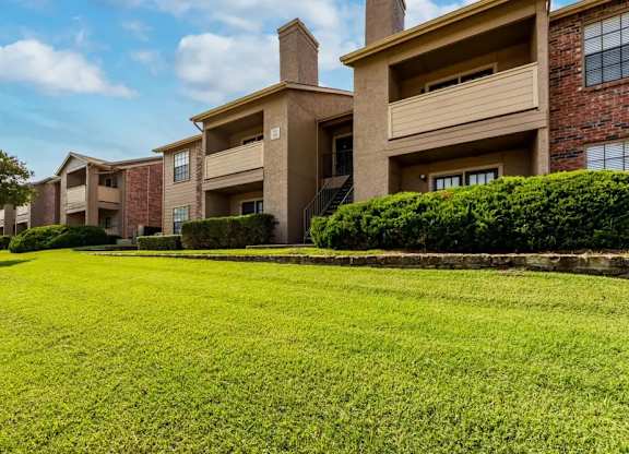 A row of apartment buildings with green lawns in front.