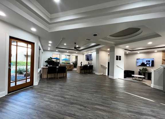 A spacious living room with a dark wood floor and white walls.