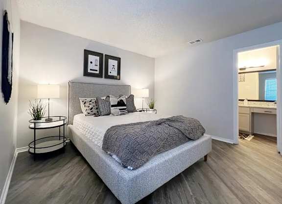 A bedroom with a bed, nightstand, and two framed pictures on the wall.