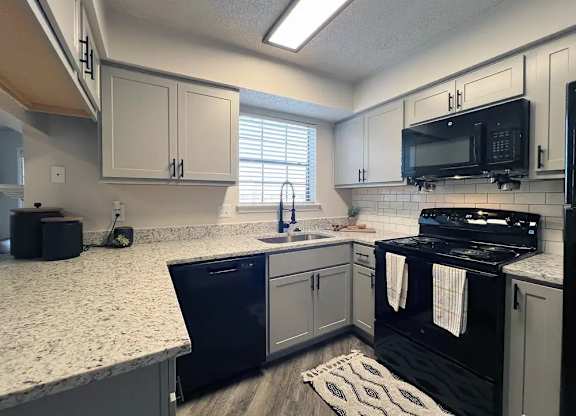 A kitchen with black appliances and white cabinets.