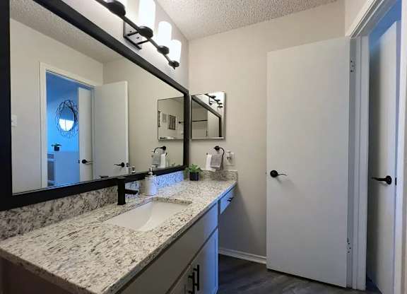 A bathroom with a marble countertop and a large mirror.