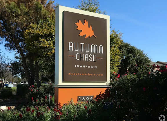 A sign for Autumn Chase Townhomes with a leaf logo and website.