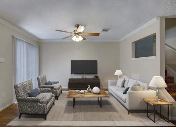 A living room with a television, two chairs, a couch, and a coffee table.