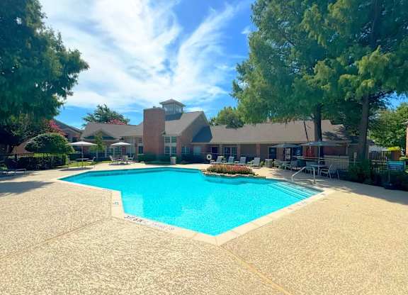 A large swimming pool in front of a building surrounded by trees.