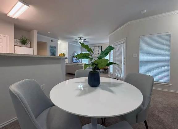 A dining room with a white table and grey chairs.
