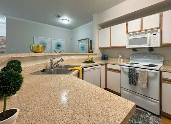 A kitchen with a countertop, sink, and stove.