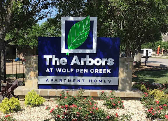 A sign for The Arbors at Wolf Pen Creek Apartment Homes.