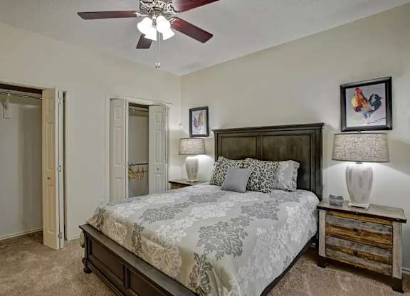 A bedroom with a large bed and a ceiling fan.