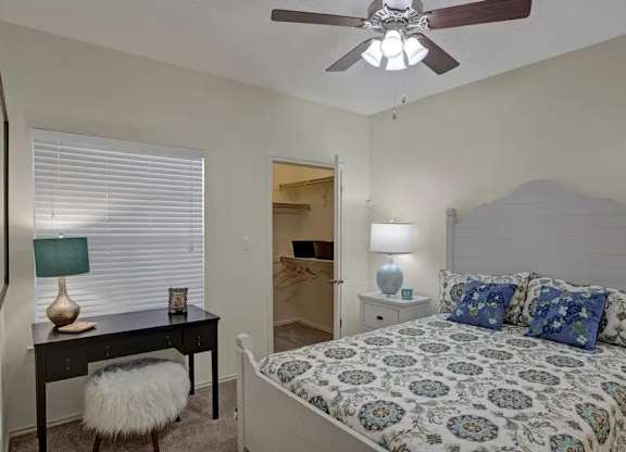 A bedroom with a bed, desk, and chair.