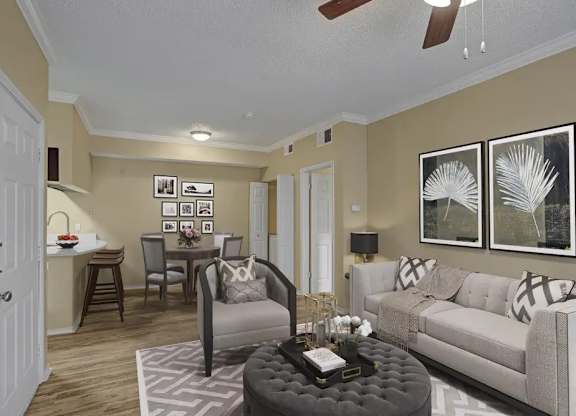 A living room with a grey ottoman and a white couch.