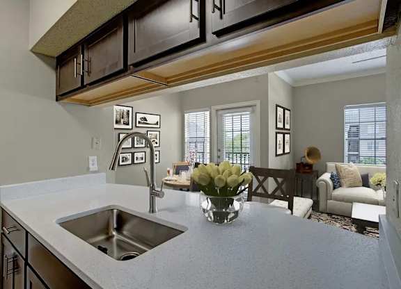 A kitchen with a sink and a countertop with a vase of flowers on it.