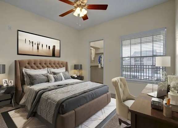 A bedroom with a large bed, a ceiling fan, and a painting on the wall.