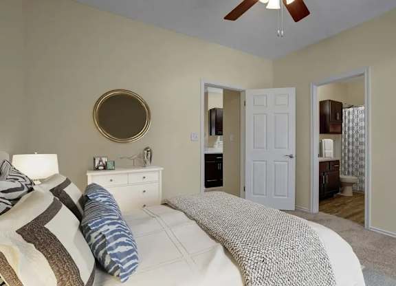 A bedroom with a bed, dresser, mirror, and a ceiling fan.