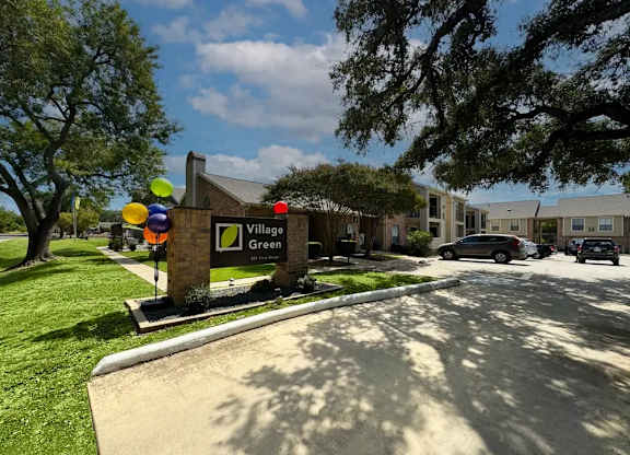 A sign for Village Green stands in front of a building.