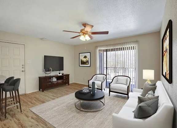 A living room with a ceiling fan and a flat screen TV.