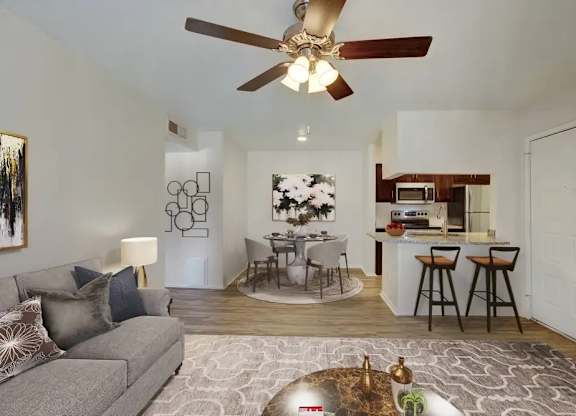 A living room with a grey couch and a ceiling fan.