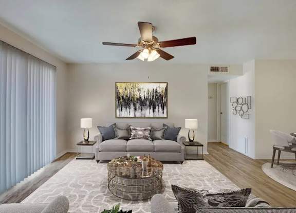 A living room with a grey couch, a coffee table, and a painting on the wall.