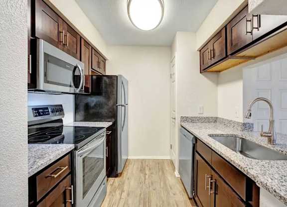 A kitchen with a black fridge and stove top oven.