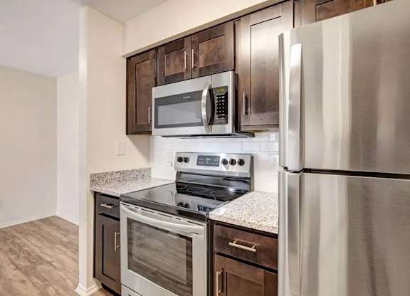 A kitchen with a stainless steel refrigerator, microwave, and oven.