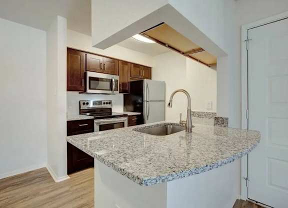 A kitchen with granite countertops and wooden cabinets.