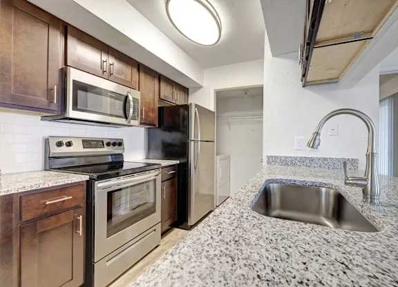 A kitchen with a granite countertop and stainless steel appliances.
