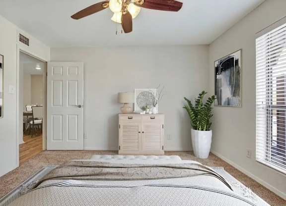 A bedroom with a bed, dresser, and ceiling fan.