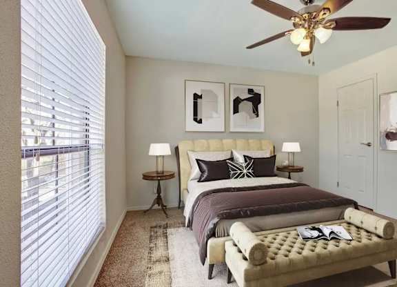 A bedroom with a bed, a bench, and a ceiling fan.