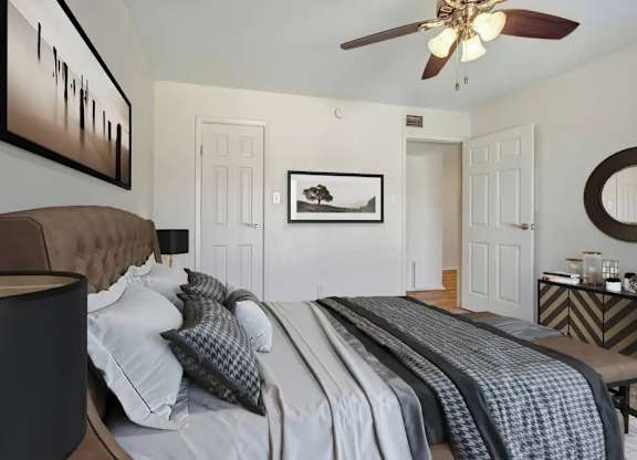 A bedroom with a large bed and a ceiling fan.