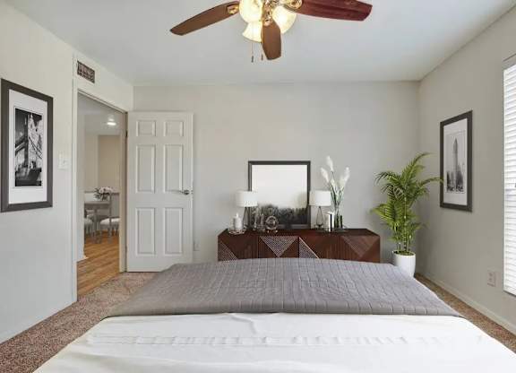 A bedroom with a bed, a ceiling fan, and a mirror.