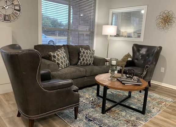 A living room with a brown leather chair and a grey couch with a wooden coffee table in between.