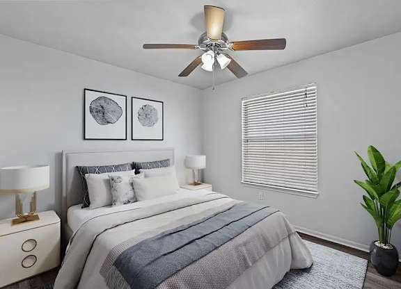 A bedroom with a bed, two lamps, a ceiling fan, and a plant.