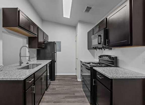 A kitchen with dark brown cabinets and black appliances.
