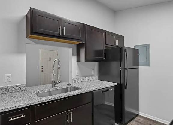 A kitchen with black cabinets and a black refrigerator.
