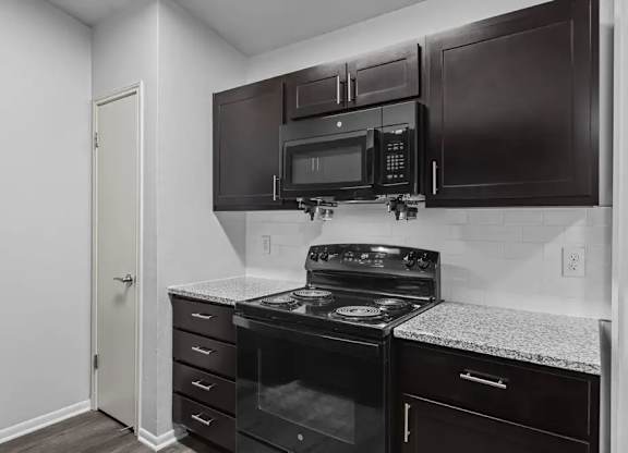 A kitchen with black cabinets and a black stove top oven.