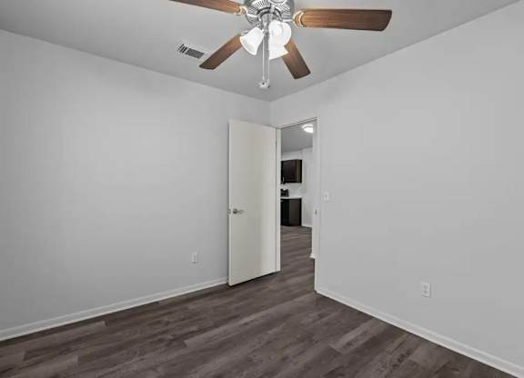 A room with a ceiling fan and a doorway leading to another room.