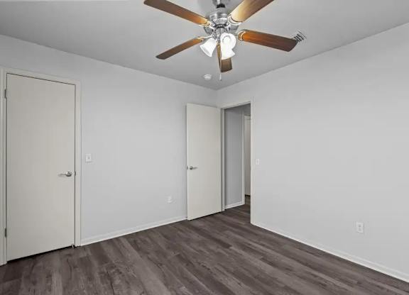 A room with a ceiling fan and wood flooring.