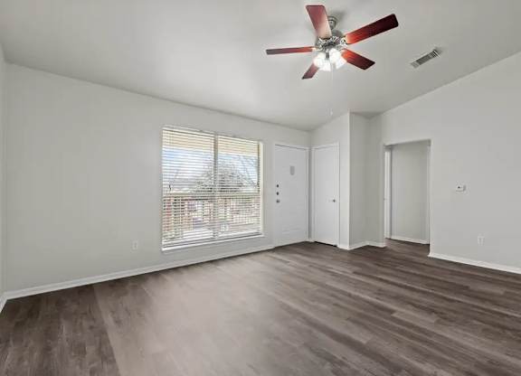 A room with a ceiling fan and a window with blinds.