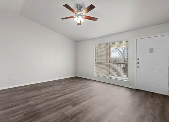A room with a ceiling fan and wooden flooring.