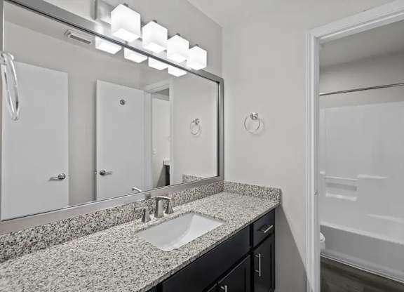 A bathroom with a sink, mirror, and a shower.