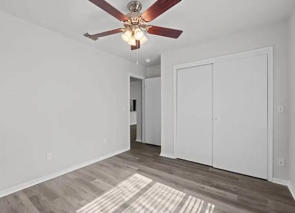 A room with a ceiling fan and wooden flooring.