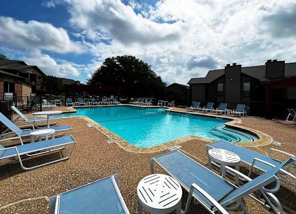 A pool surrounded by chairs and umbrellas.
