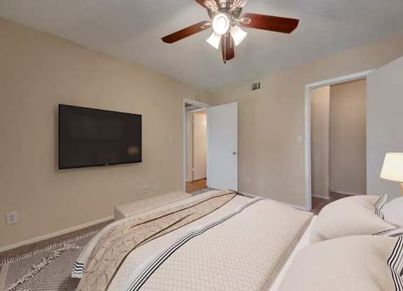 A bedroom with a large bed and a flat screen TV mounted on the wall.